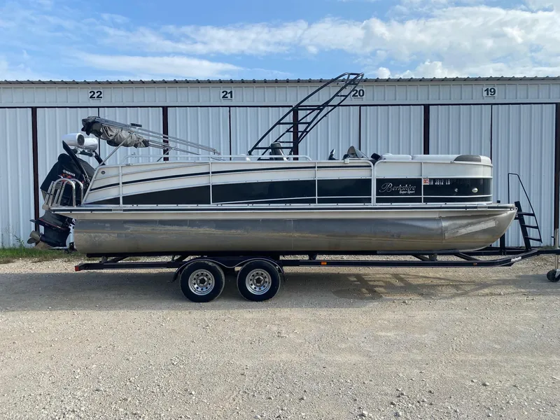 The Image of 2015 Berkshire 233SL STS pontoon boat on trailer, parked in front of storage units. - 0