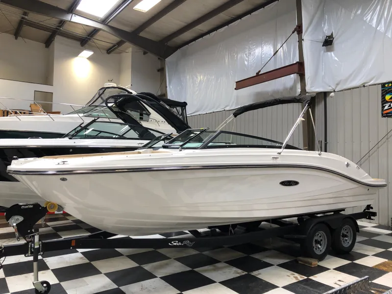 The Image of 2025 Sea Ray SPX 230 boat on trailer in showroom. - 1