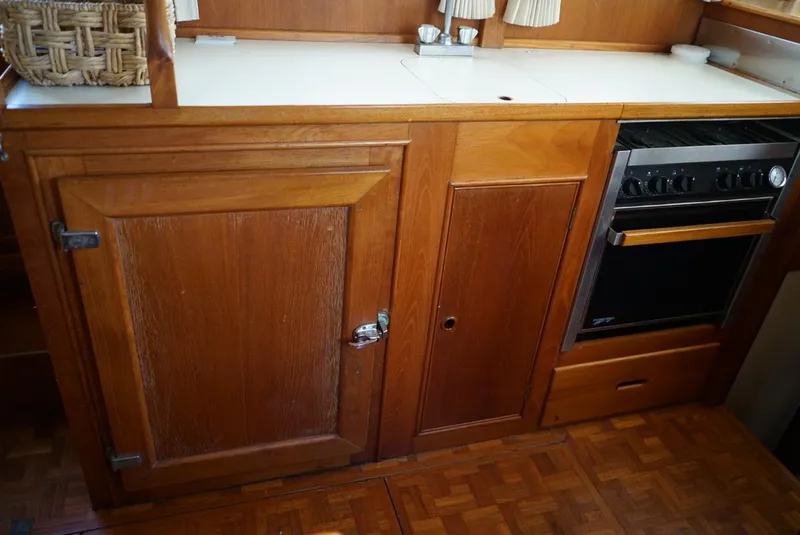 Slide: The Image of Wooden kitchen area in a 1986 Grand Banks 36 Classic boat, featuring cabinets and a stove. - 19