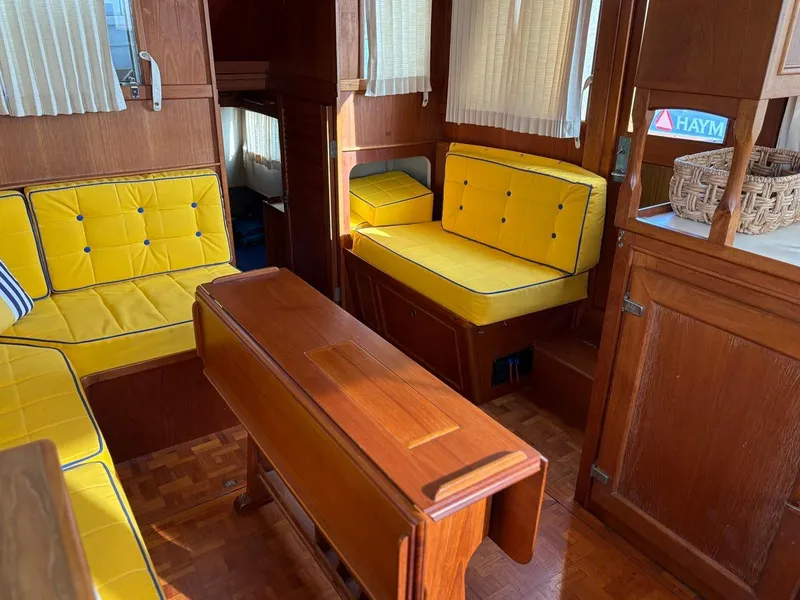 Slide: The Image of Interior of 1986 Grand Banks 36 Classic with yellow cushioned seating and wooden table. - 23