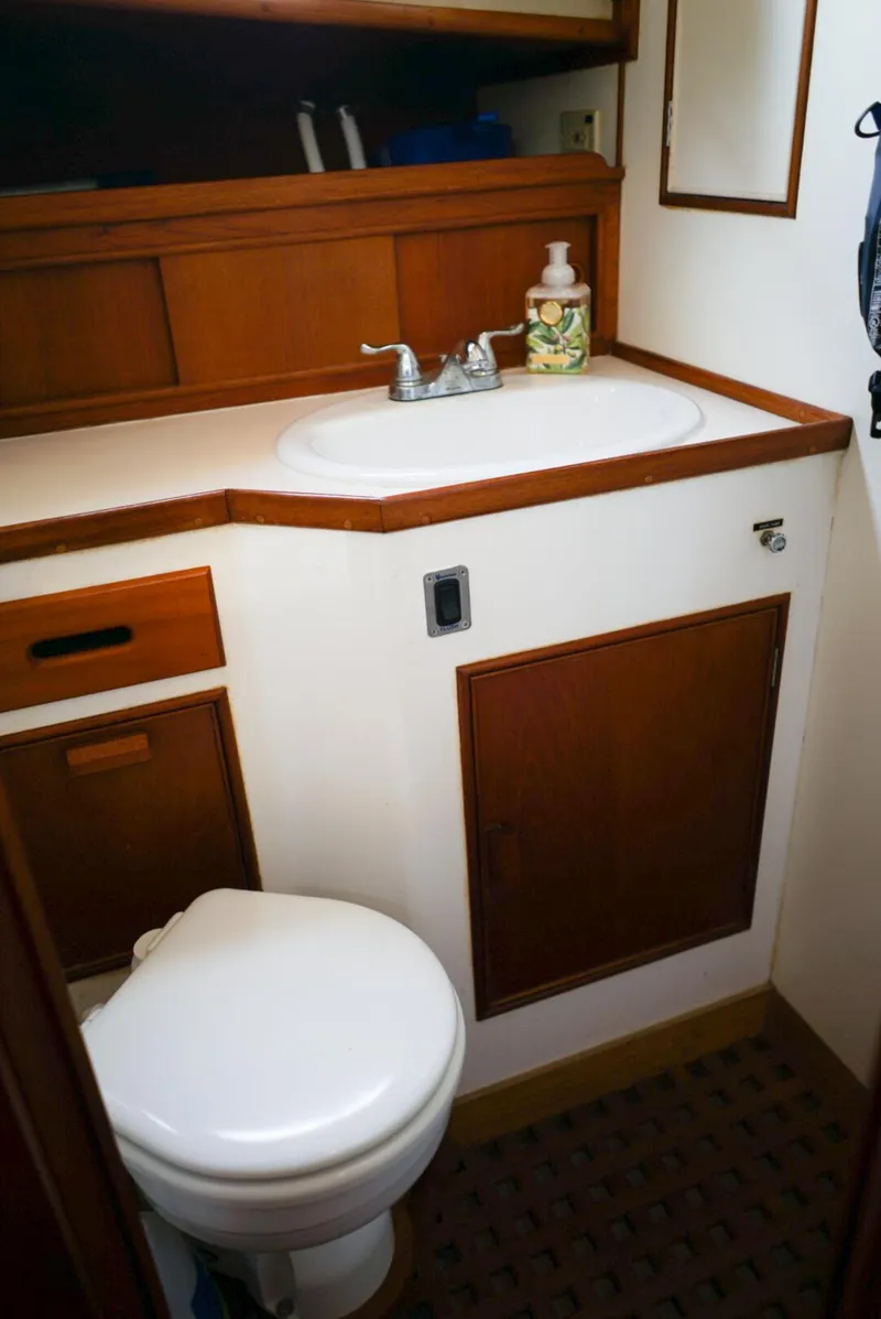 Slide: The Image of 1986 Grand Banks 36 Classic boat bathroom with sink and toilet, featuring wooden cabinetry. - 27