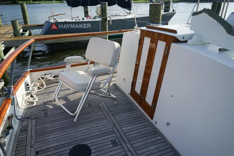 Slide: The Image of 1986 Grand Banks 36 Classic yacht deck with chair and wooden door, docked by water. - 7
