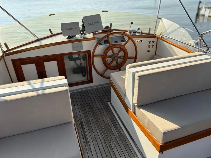 Slide: The Image of Helm of 1986 Grand Banks 36 Classic with Garmin navigation, wooden wheel, and cushioned seating. - 9