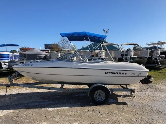Slide: The Image of 2001 Stingray 180 LS/LX boat on trailer with blue canopy, parked outdoors. - 25