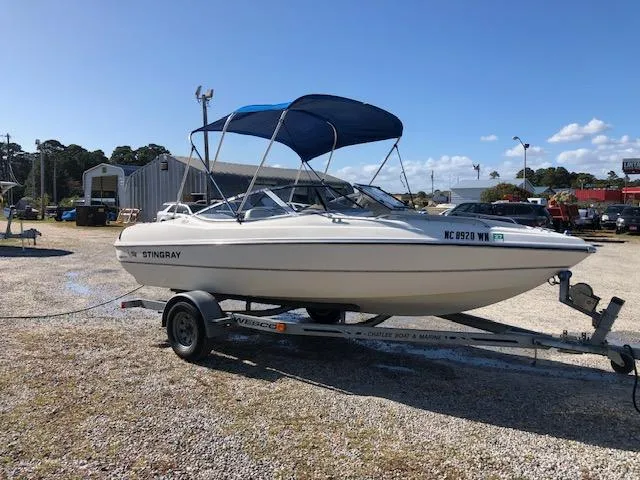 Slide: The Image of 2001 Stingray 180 LS/LX boat on trailer with blue canopy in outdoor setting. - 26