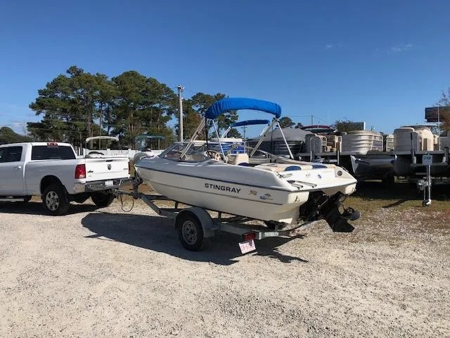Slide: The Image of 2001 Stingray 180 LS/LX boat on trailer, parked near white truck, sunny day. - 5