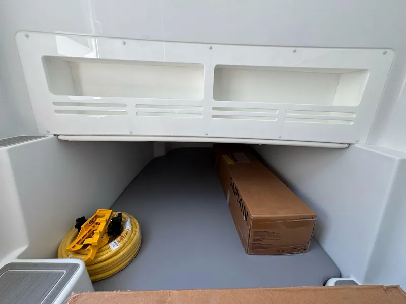 Slide: The Image of Storage compartment of 2026 Invincible 43 Open Fisherman with hose and Garmin box. - 21