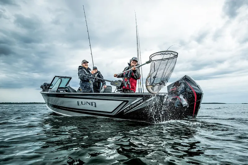 Slide: The Image of Manufacturer Provided Image: 2025 Lund 2075 Fisherman boat with anglers on a lake under cloudy skies. - 18