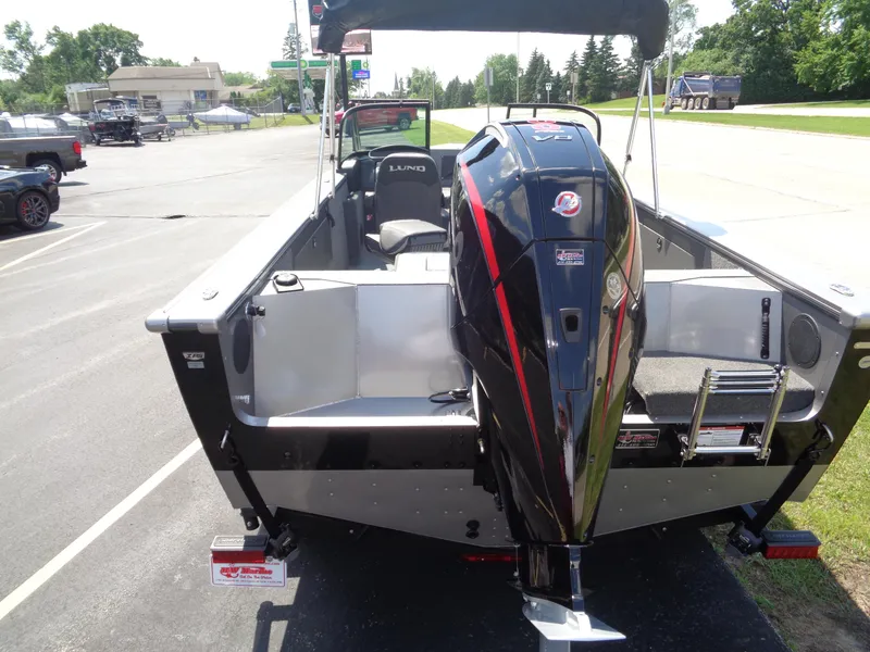 Slide: The Image of 2025 Lund 2075 Fisherman boat with powerful outboard motor, parked on a sunny day. - 2
