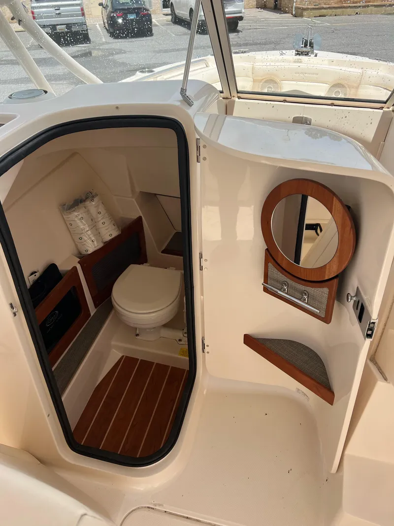 Slide: The Image of 2019 Grady-White Freedom 235 boat interior with compact bathroom and wooden accents. - 5