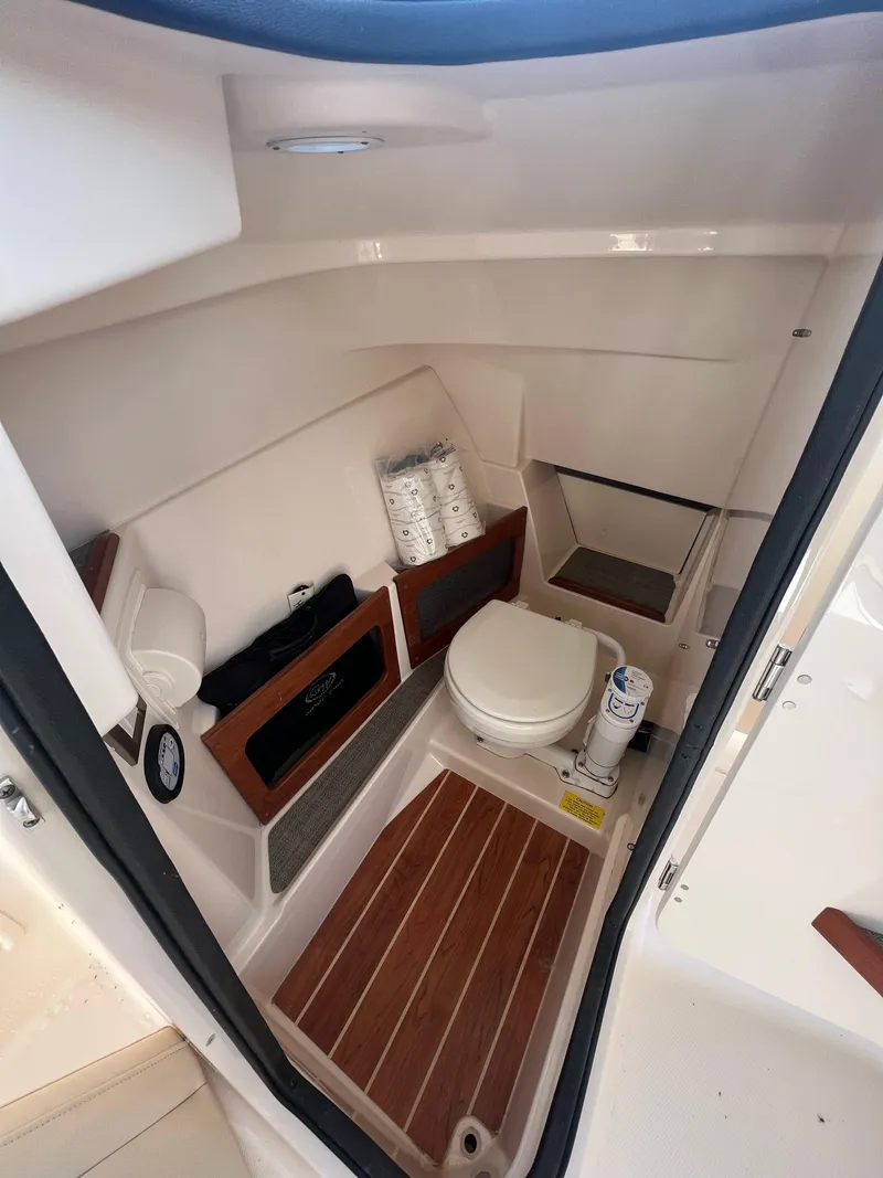 Slide: The Image of 2019 Grady-White Freedom 235 boat interior with compact bathroom and wooden flooring. - 7