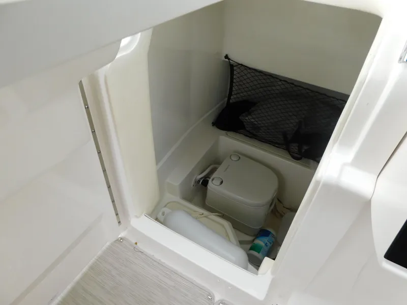 Slide: The Image of 2021 Sea Ray SDX 250 boat interior with compact toilet and storage area. - 14