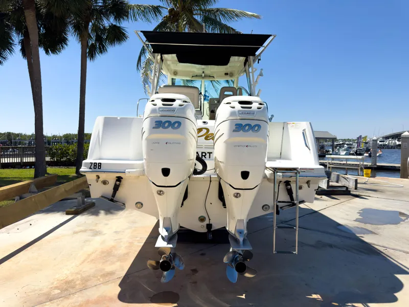 Slide: The Image of 2018 Boston Whaler 315 Conquest with twin 300 horsepower engines, docked under palm trees. - 10