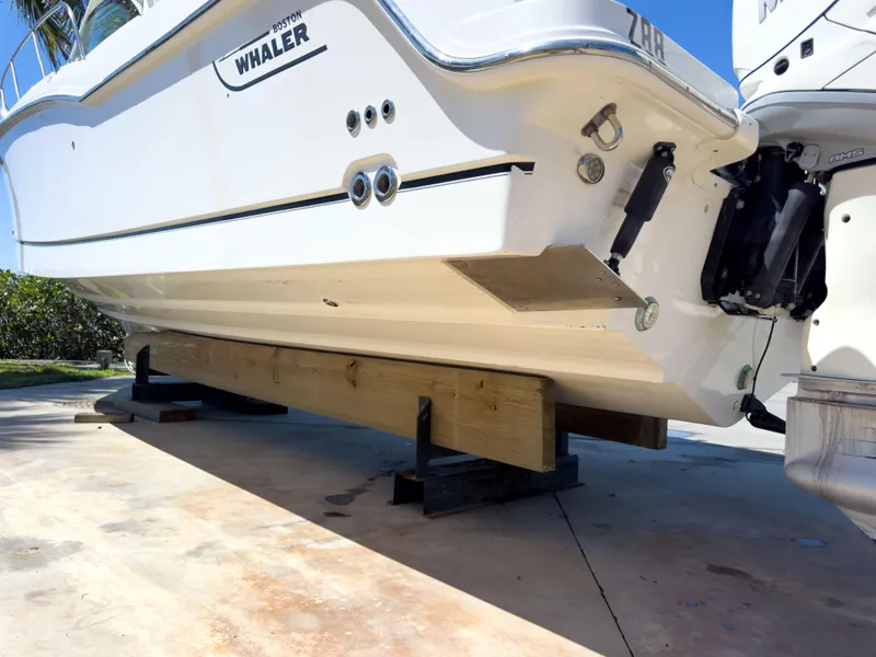 Slide: The Image of 2018 Boston Whaler 315 Conquest boat on wooden supports, viewed from the stern. - 12