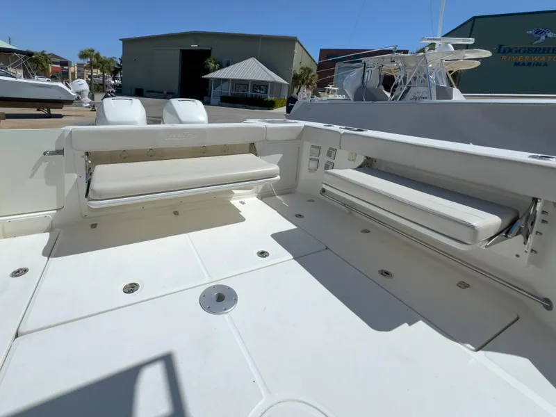 Slide: The Image of 2018 Boston Whaler 315 Conquest boat deck with foldable seating in marina setting. - 19