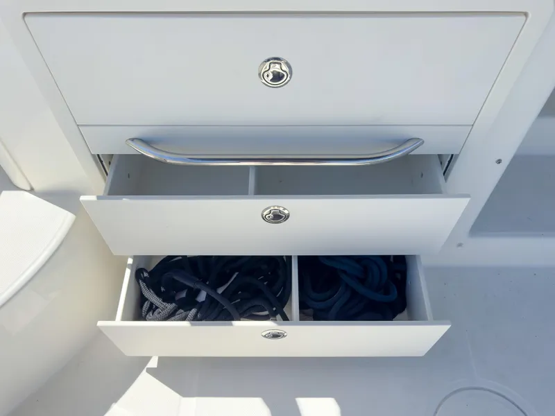 Slide: The Image of Open storage drawers on a 2018 Boston Whaler 315 Conquest boat, containing ropes. - 27