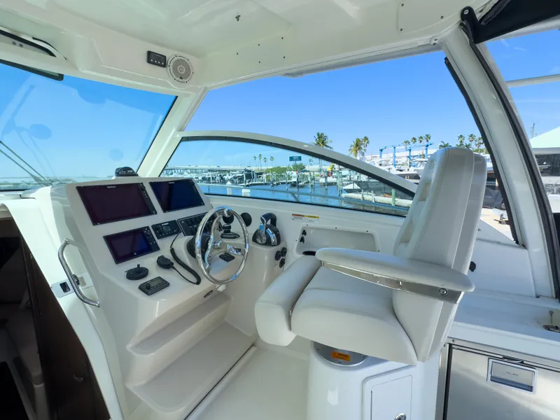 Slide: The Image of 2018 Boston Whaler 315 Conquest helm with modern controls and marina view. - 29