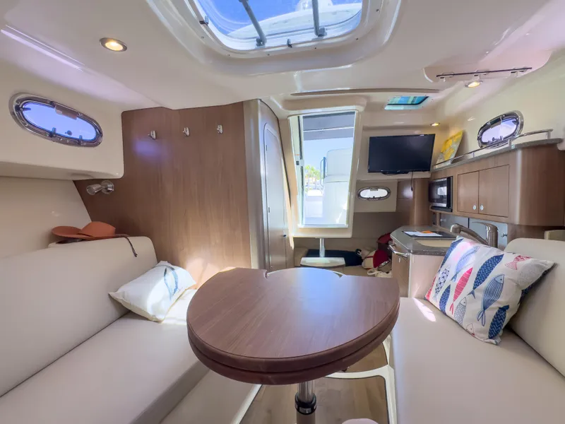 Slide: The Image of 2018 Boston Whaler 315 Conquest cabin interior with seating, table, and kitchenette. - 34