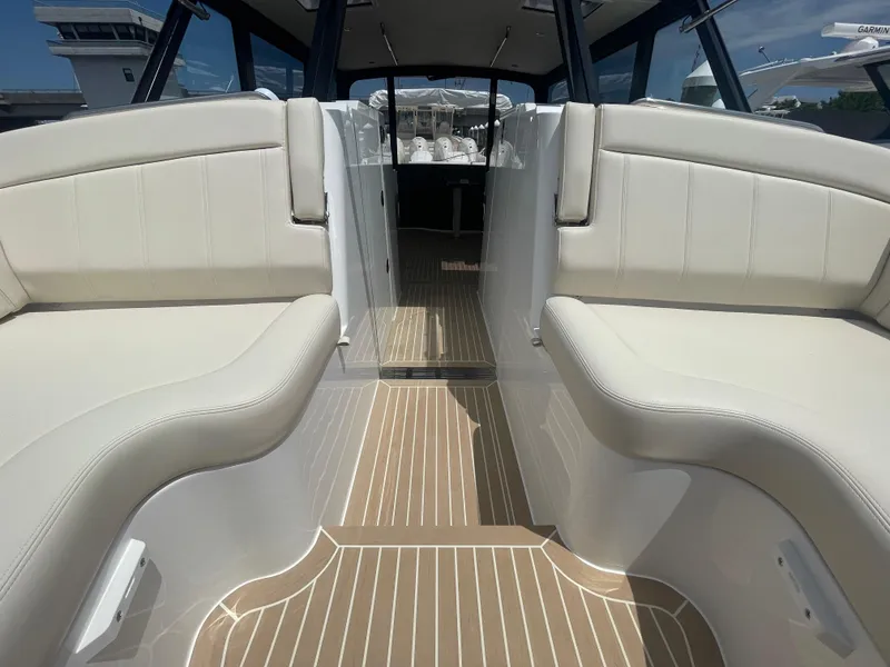 Slide: The Image of 2025 MJM 3 boat interior with beige seating and wood-patterned flooring. - 17