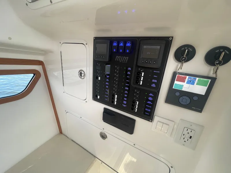 Slide: The Image of Control panel of 2025 MJM 3 boat with switches, gauges, and key hooks. - 20