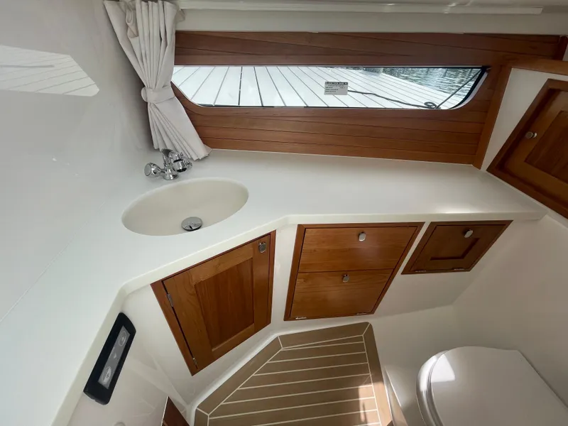 Slide: The Image of MJM 3 2025 boat interior bathroom with wooden cabinets, sink, and window. - 22