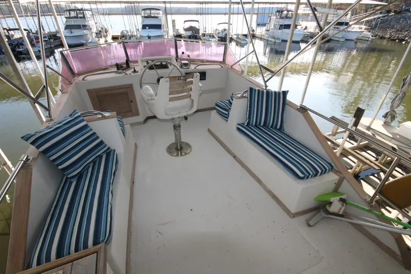 Slide: The Image of 1986 Senator 35 Sundeck Trawler with striped seating, docked at a marina. - 13