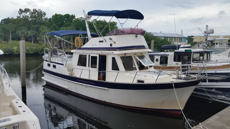 Slide: The Image of 1986 Senator 35 Sundeck Trawler docked in a marina, featuring classic design and blue accents. - 2