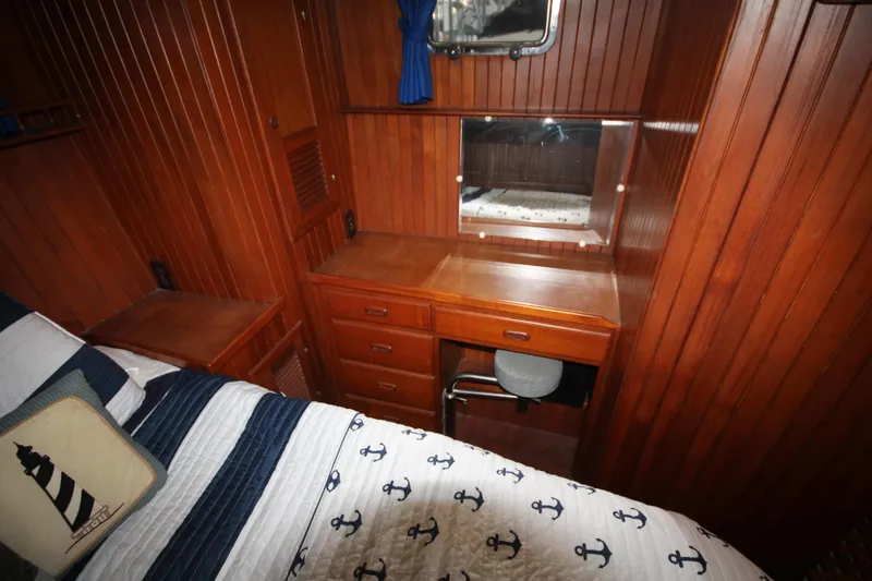 Slide: The Image of 1986 Senator 35 Sundeck Trawler cabin with wooden interior and nautical-themed bedding. - 35