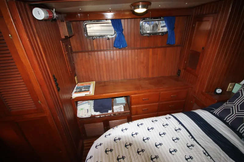Slide: The Image of 1986 Senator 35 Sundeck Trawler cabin with wood paneling, bed, and storage drawers. - 36
