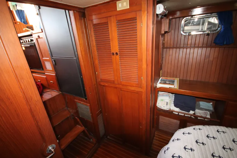 Slide: The Image of 1986 Senator 35 Sundeck Trawler interior with wooden cabinetry and nautical-themed bedding. - 37