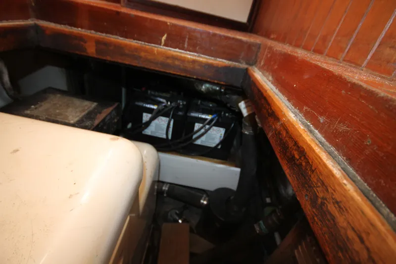 Slide: The Image of 1986 Senator 35 Sundeck Trawler engine compartment with visible batteries and wooden paneling. - 40