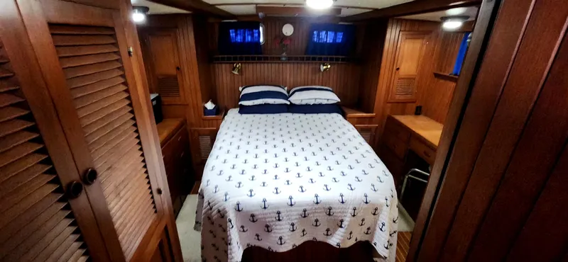 Slide: The Image of Cozy bedroom in 1986 Senator 35 Sundeck Trawler with nautical-themed bedding and wooden interior. - 49