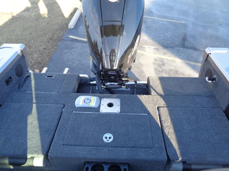 Slide: The Image of 2025 Lund 1875 Tyee boat interior with motor, featuring carpeted deck and storage compartments. - 11