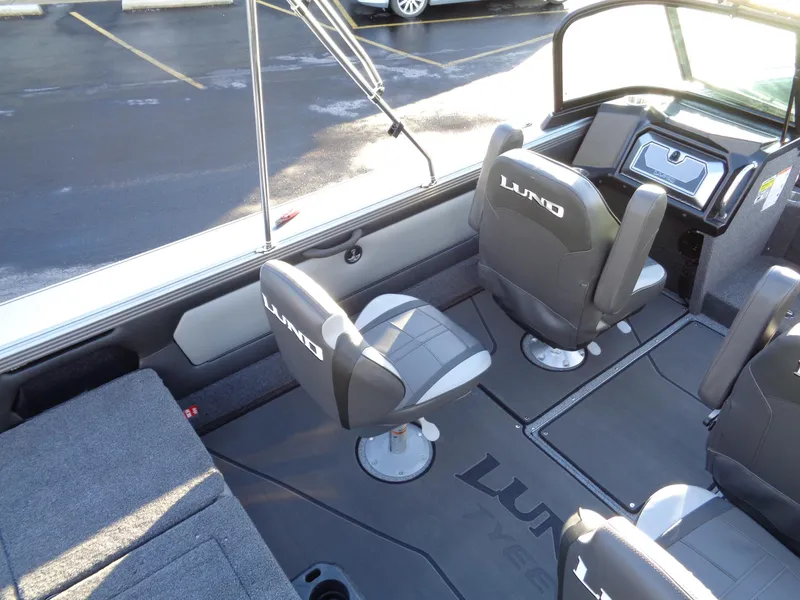 Slide: The Image of 2025 Lund 1875 Tyee boat interior with seating and dashboard, parked on asphalt. - 14