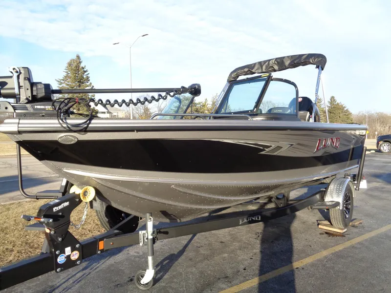 Slide: The Image of 2025 Lund 1875 Tyee boat on trailer, black exterior, parked outdoors. - 2