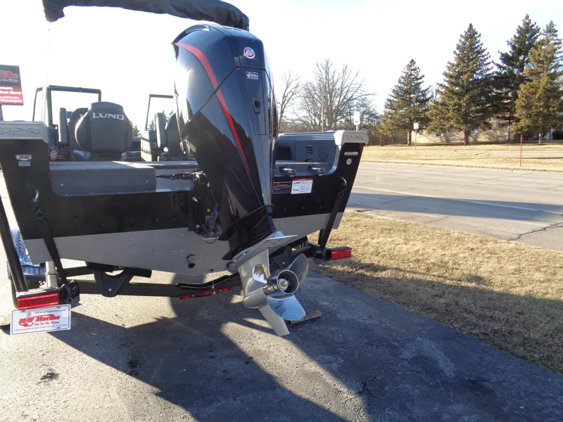 Slide: The Image of 2025 Lund 1875 Tyee boat with powerful outboard motor, parked on pavement. - 6