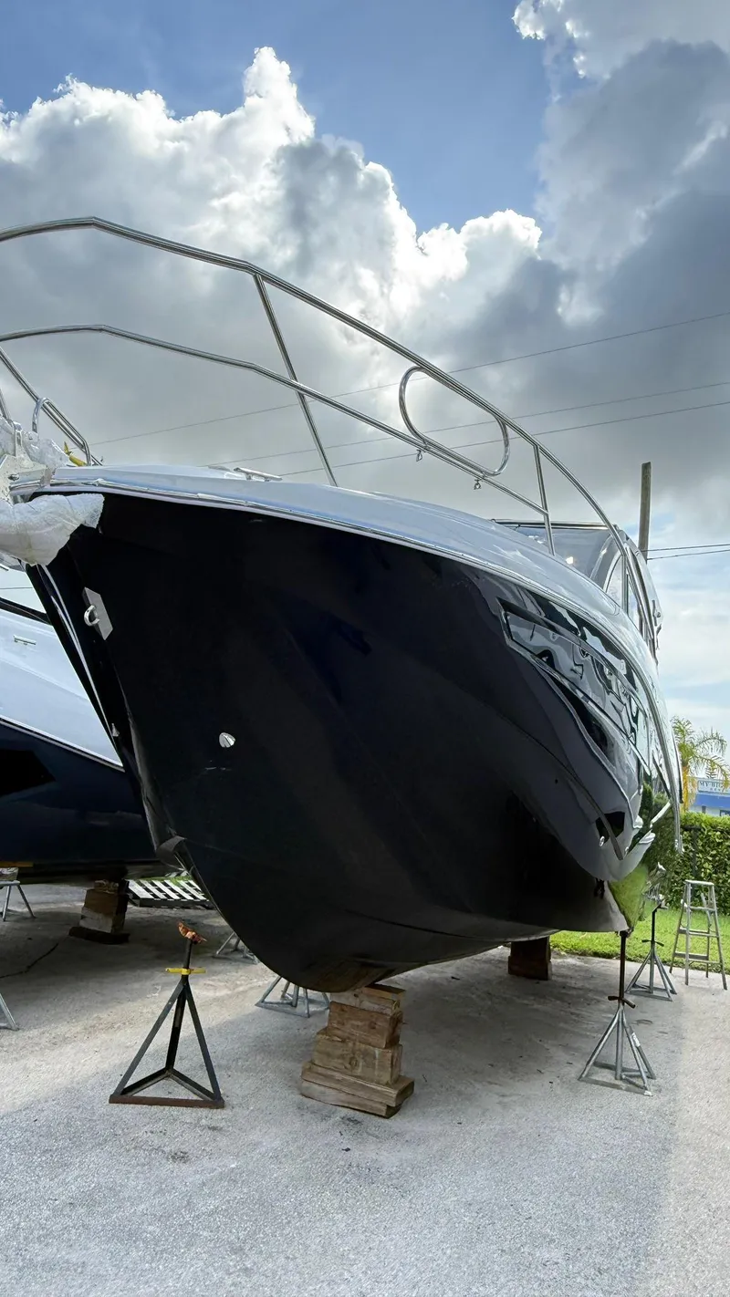 Slide: The Image of 2025 NX Boats NX370 HT on stands, showcasing sleek design under a cloudy sky. - 3