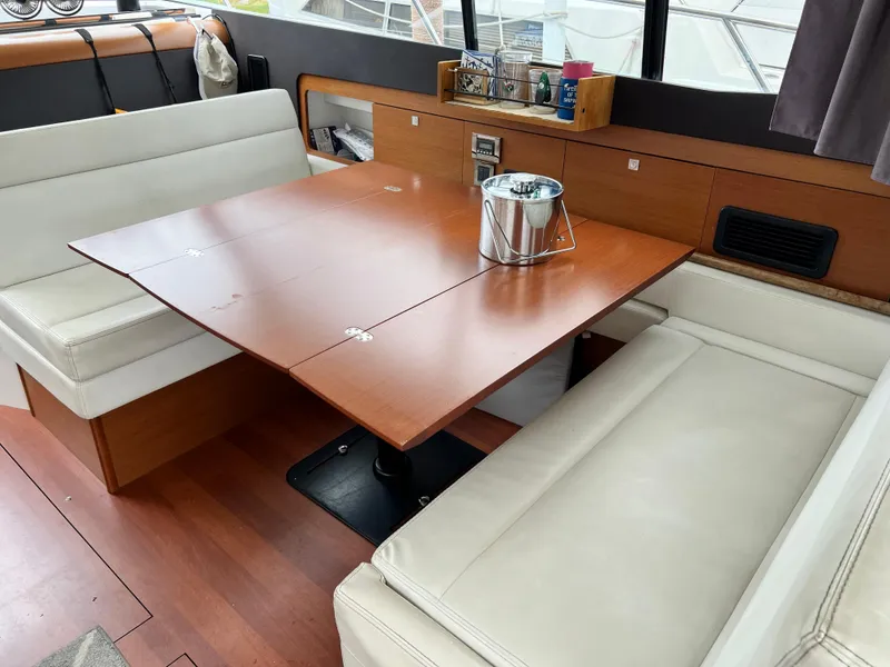 Slide: The Image of Interior of 2017 Jeanneau NC11 yacht with wooden table and white seating. - 12