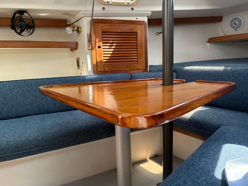 Slide: The Image of Cozy interior of a 1994 Catalina 270 LE sailboat with wooden table and blue seating. - 31