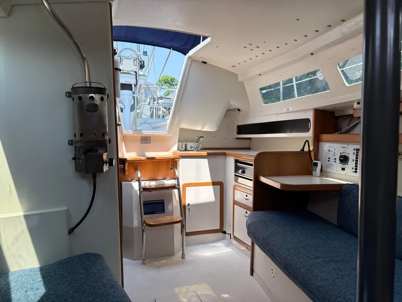 Slide: The Image of Interior of a 1994 Catalina 270 LE sailboat, featuring a compact kitchen and seating area. - 34