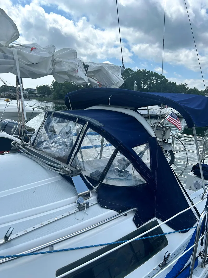 Slide: The Image of 1994 Catalina 270 LE sailboat with blue canopy and American flag, docked under cloudy sky. - 9