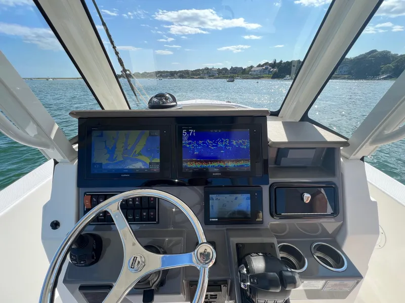 Slide: The Image of 2019 Pursuit S 288 boat dashboard with navigation screens and steering wheel on open water. - 12