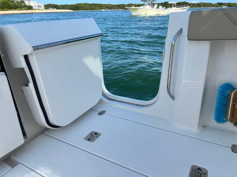 Slide: The Image of 2019 Pursuit S 288 boat interior with open door, overlooking water and distant boats. - 16