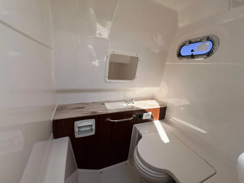 Slide: The Image of 2019 Pursuit S 288 boat interior bathroom with sink, toilet, and porthole window. - 19