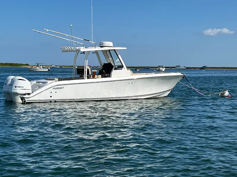 Slide: The Image of 2019 Pursuit S 288 boat anchored on calm water under clear blue sky. - 2