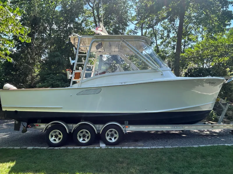 Slide: The Image of 1996 Tides 27 boat on trailer, surrounded by lush greenery. - 3