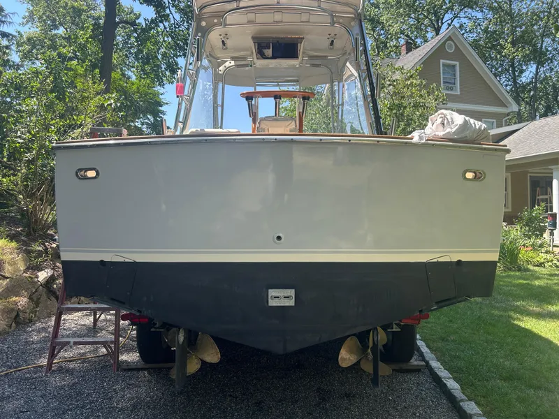 Slide: The Image of 1996 Tides 27 boat on trailer, parked in a residential yard with trees and house. - 7