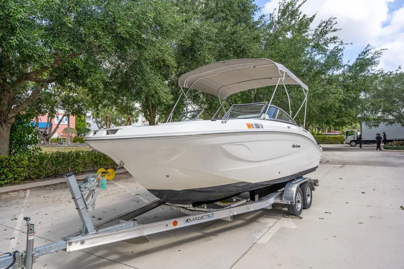 Slide: The Image of 2025 Hurricane SunDeck 2050 OB boat on trailer, parked outdoors. - 2