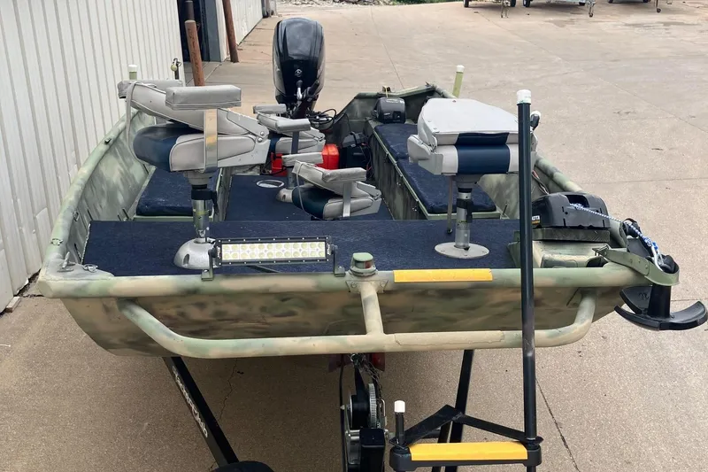 Slide: The Image of 2012 Steven Custom JON EXTRA WIDE boat with seating and motor, parked on concrete. - 19