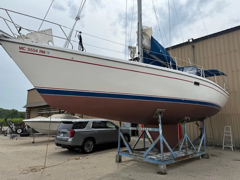 The Image of 1998 Catalina 42Mk 2 sailboat on a stand, with a car and building nearby. - 0